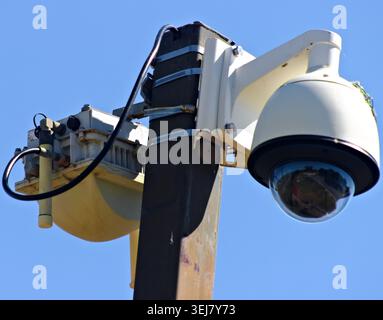 Primo piano di una telecamera di sicurezza montata su palo e di un'apparecchiatura di sorveglianza contro un cielo azzurro Foto Stock