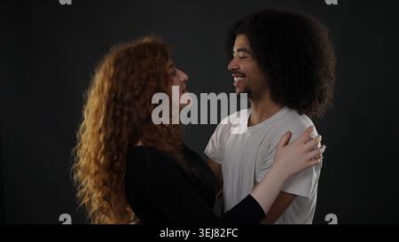 Felice giovane coppia che esprime amore e felicità mentre abbraccia in uno studio Foto Stock