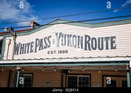 Skagway, Alaska - 28 agosto 2025: Primo piano della facciata in legno d'epoca e dei segni dipinti dello storico White Pass & Yukon Route, partenza dalla stazione ferroviaria Foto Stock