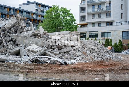 Un mucchio di macerie di cemento demolite di fronte ad un moderno edificio residenziale. Foto Stock