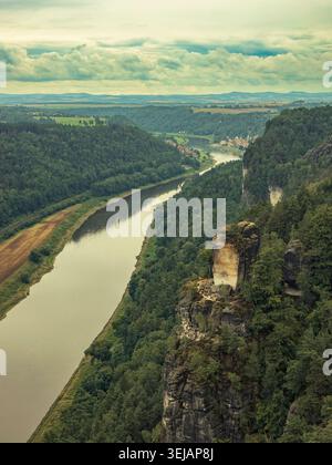 Lohmen, Germania - 06.08.2023: Veduta aerea del fiume che scorre tra fitte foreste e ripide formazioni rocciose sotto la nuvolosa luce del giorno Foto Stock