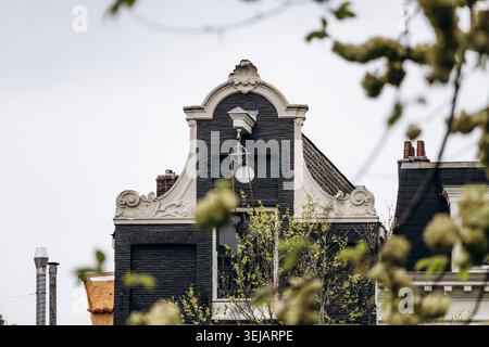 Tetti decorati in nero della casa sul canale olandese con dettagli decorativi a timpano nella storica Amsterdam Foto Stock