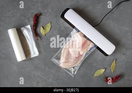 Filetto di tilapia in un sacchetto sottovuoto. Imballaggio sottovuoto di pesce. L'uso di un sigillante sottovuoto per lo stoccaggio a lungo termine dei prodotti. Vista dall'alto. Posizione piatta Foto Stock