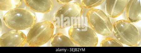 Primo piano di capsule in gel giallo trasparente lucido con illuminazione soffusa Foto Stock