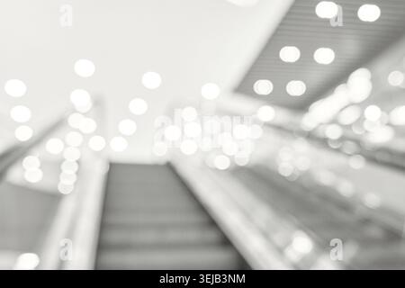 Immagine astratta sfocata di scala mobile con luci bokeh luminose nel moderno centro commerciale Foto Stock