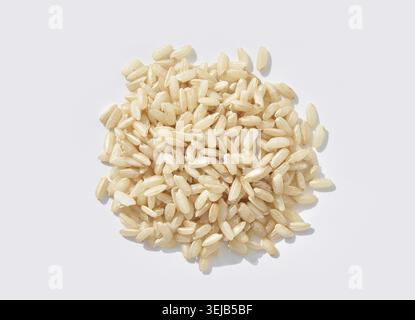 Riso al gelsomino marrone grani crudi sparsi su sfondo bianco, vista dall'alto ravvicinata Foto Stock