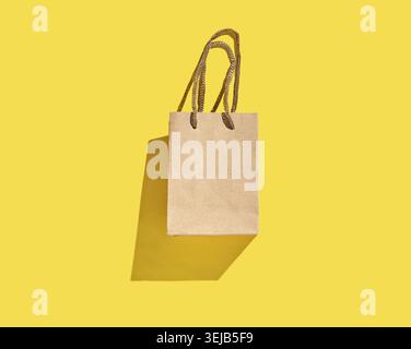 Borsa per la spesa in carta marrone con manici su sfondo giallo brillante Foto Stock