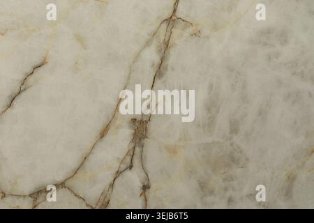 Questa vista ravvicinata presenta una superficie in marmo liscio con delicate venature dorate intrecciate con un morbido sfondo grigio, perfetto per il design Foto Stock