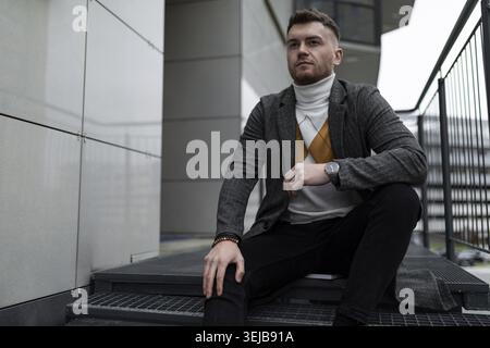 Uomo serio seduto fuori a guardare la telecamera Foto Stock