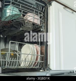 Lavastoviglie aperta con piatti e utensili puliti pronti per essere scaricati in cucina Foto Stock