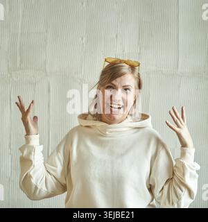 Donna caucasica matura in abbigliamento casual sorridente entusiasticamente su sfondo murale testurizzato Foto Stock
