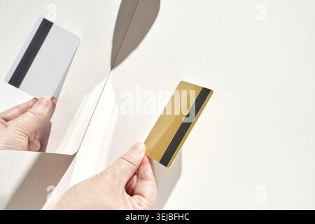Mani che tengono la carta di credito e riflettono sullo sfondo bianco Foto Stock