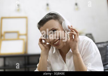 Allegra donna matura che sorride con le cuffie Foto Stock