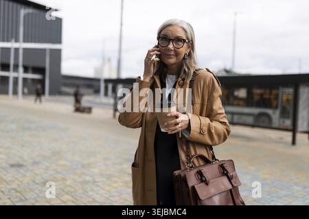 Donna d'affari caucasica senior che parla al telefono cellulare all'esterno Foto Stock
