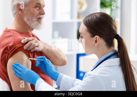 Infermiera in guanti medici che vaccinano l'uomo in ospedale Foto Stock