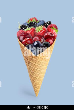 Bacche fresche in cono per waffle su sfondo blu pastello Foto Stock