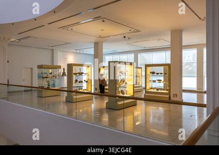 Visitatore osserva vetrine illuminate con ceramiche e opere in metallo islamiche in una galleria moderna al Museo delle Arti Islamiche, Kuala Lumpur, Malesia Foto Stock