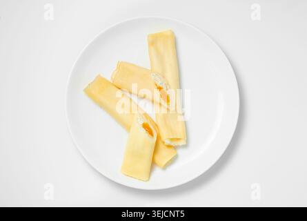 Pancake sottili arrotolati dolci tagliati a metà con formaggio di casa e confettura d'arancia Foto Stock
