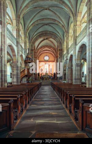 Andlau, Francia - 12.08.2023: Grande vista della navata centrale in Église Saint-Pierre-et-Paul con pulpito ornato, altare e rosone Foto Stock