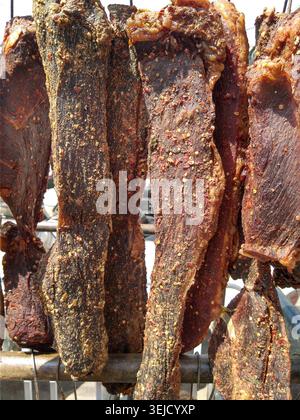 Primo piano di carne speziata essiccata all'aria, una prelibatezza tradizionale cinese, appesa in vendita in un mercato umido locale a Kunming, Yunnan. Foto Stock