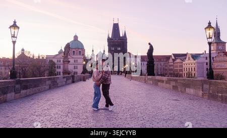 Mentre il sole tramonta su Praga, una coppia condivide un tenero abbraccio sul Ponte Carlo. Foto Stock