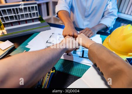 Ingegneri e architetti analizzano i modelli di costruzione e discutono le strategie di progetto, combinando conoscenze tecniche e idee creative per ottenere successo Foto Stock