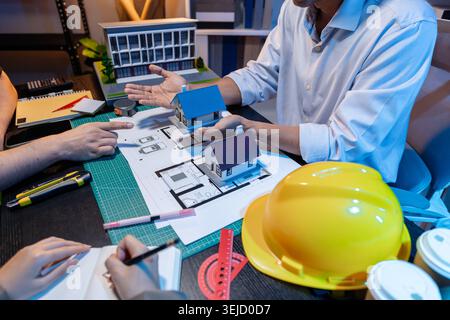 Ingegneri e architetti analizzano i modelli di costruzione e discutono le strategie di progetto, combinando conoscenze tecniche e idee creative per ottenere successo Foto Stock