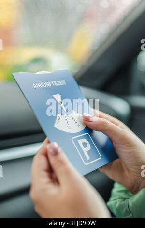 Prima di lasciare il veicolo, il conducente tiene il disco di parcheggio europeo all'interno dell'auto parcheggiata Foto Stock