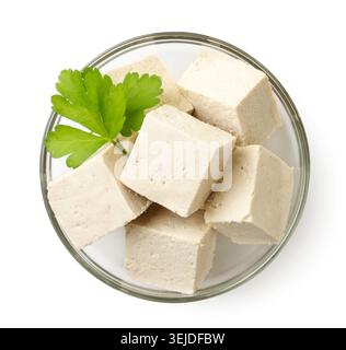 Tofu tagliato a dadini con prezzemolo in un piatto da vicino su fondo bianco, isolato. La vista dall'alto Foto Stock