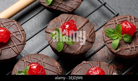 Brownie al cioccolato splendidamente condite con ciliegie rosse brillanti e foglie di menta fresca, collocate su una griglia di raffreddamento per un'elegante serata Foto Stock