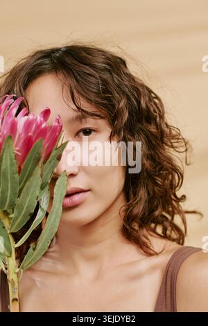 Ritratto di donna asiatica adulta che tiene il fiore per il marchio di bellezza Foto Stock