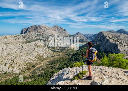 Escursionista donna con zaino che guarda il bacino idrico di Cúber da Puig Lofre, area naturale Serra de Tramuntana, Maiorca, Spagna Foto Stock