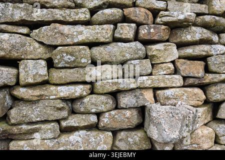Tradizionale parete in pietra secca realizzata con blocchi di calcare irregolari ricoperti di lichene. Struttura rustica di confine del campo rurale nel Regno Unito. Foto Stock