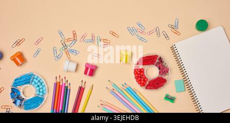 Piatto di colorate forniture scolastiche e per ufficio, tra cui matite, graffette, quaderni, vernici e affilatrici su un bac pesca Foto Stock