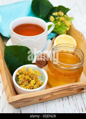 Tazza di tè alle erbe con fiori di tiglio su un vecchio sfondo di legno Foto Stock