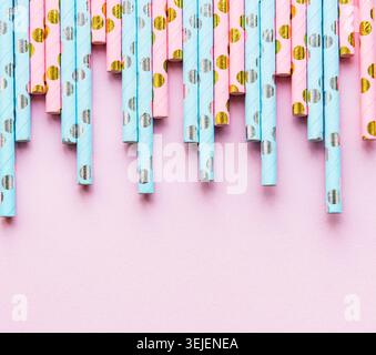 Bevi cannucce tratteggiate per una festa su sfondo rosa con spazio per le copie. Vista dall'alto delle cannucce ecocompatibili monouso di carta colorata Foto Stock