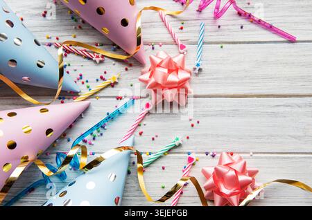 Buon compleanno o feste. Cappelli da compleanno, coriandoli e nastri piatti su sfondo bianco in legno. Vista dall'alto. Co Foto Stock
