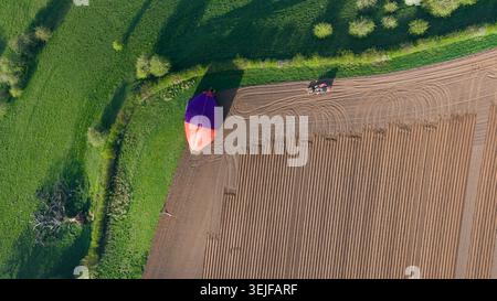 Mongolfiera e trattore sui terreni agricoli, creando un contrasto nell'Inghilterra rurale primaverile Foto Stock