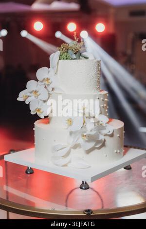 Elegante torta nuziale bianca con delicate orchidee Foto Stock