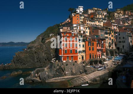 Case colorate sorgono sulle scogliere che si affacciano sul mare a Riomaggiore a mezzogiorno nelle cinque Terre Foto Stock
