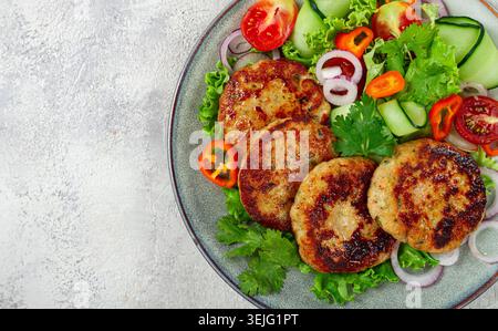 Cotolette di pollo fritte, pollo tritato, con verdure, su grigio , con insalata di verdure, vista dall'alto, fatti in casa, senza persone, Foto Stock