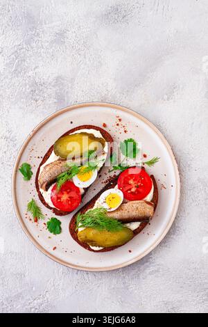 Panini con pane di segale, con spratti, uova di quaglia, pomodori freschi e cetrioli sottaceto, antipasto, colazione, fatti in casa, Foto Stock
