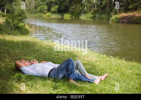 Felice coppia anziana stesa sull'erba Foto Stock