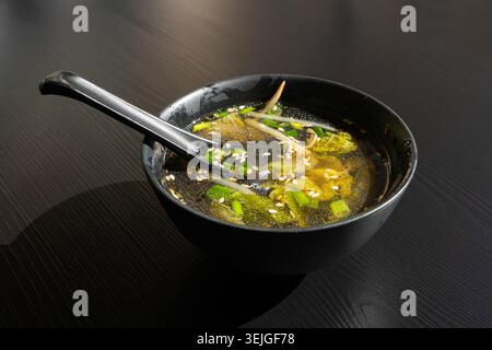 Brodo di pesce con verdure, semi di sesamo ed erbe aromatiche, brodo trasparente, ramen Shio, brodo di salmone, zuppa giapponese in ciotole nere Foto Stock