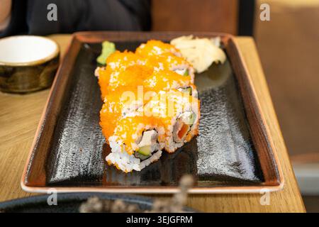 Maki Sushi, California Rolls con cetriolo, avocado, pesce crudo e caviale Red Tobiko, Makizushi con trota cruda sul piatto del ristorante, cucina tradizionale asiatica Foto Stock