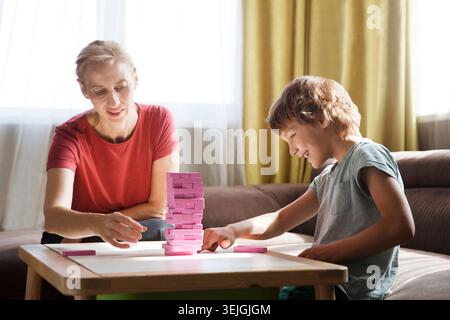 Mamma e due bambini giocano insieme a casa. La famiglia si diverte a giocare a casa. Giochi da tavolo per famiglie. Foto Stock