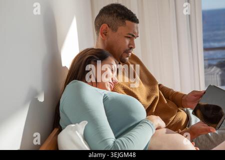 Diverse coppie sdraiate sul telaio del letto in camera da letto, con tablet con cuscino bianco e tende. Romanticismo, relax, intimità, Foto Stock