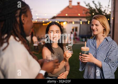 Diverse donne e amiche che si divertono con una festa in giardino con un drink Foto Stock