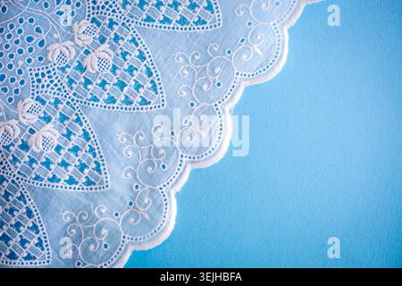 Motivo in pizzo, dettaglio di una tovaglia isolata su sfondo blu. Confine artistico. Artigianato, vintage. Concetto di hobby. Vista dall'alto. Foto Stock