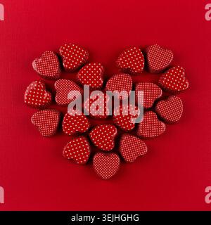 Cuore rosso di piccoli cuori su sfondo di carta rosso intenso. San Valentino. Foto Stock